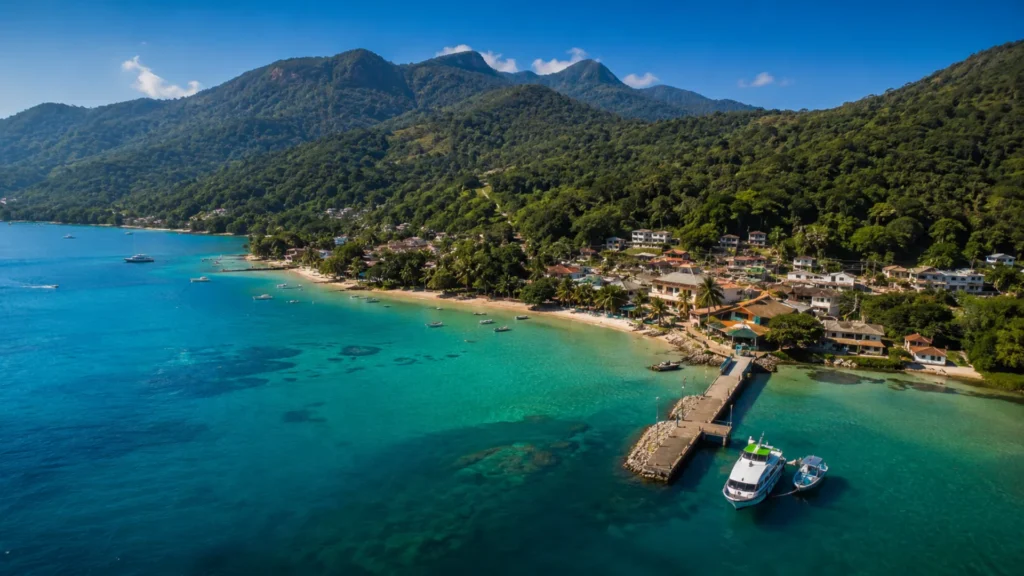 Lancha chegando à Vila do Abraão na Ilha Grande durante um dia ensolarado, com águas cristalinas e Mata Atlântica ao fundo.
